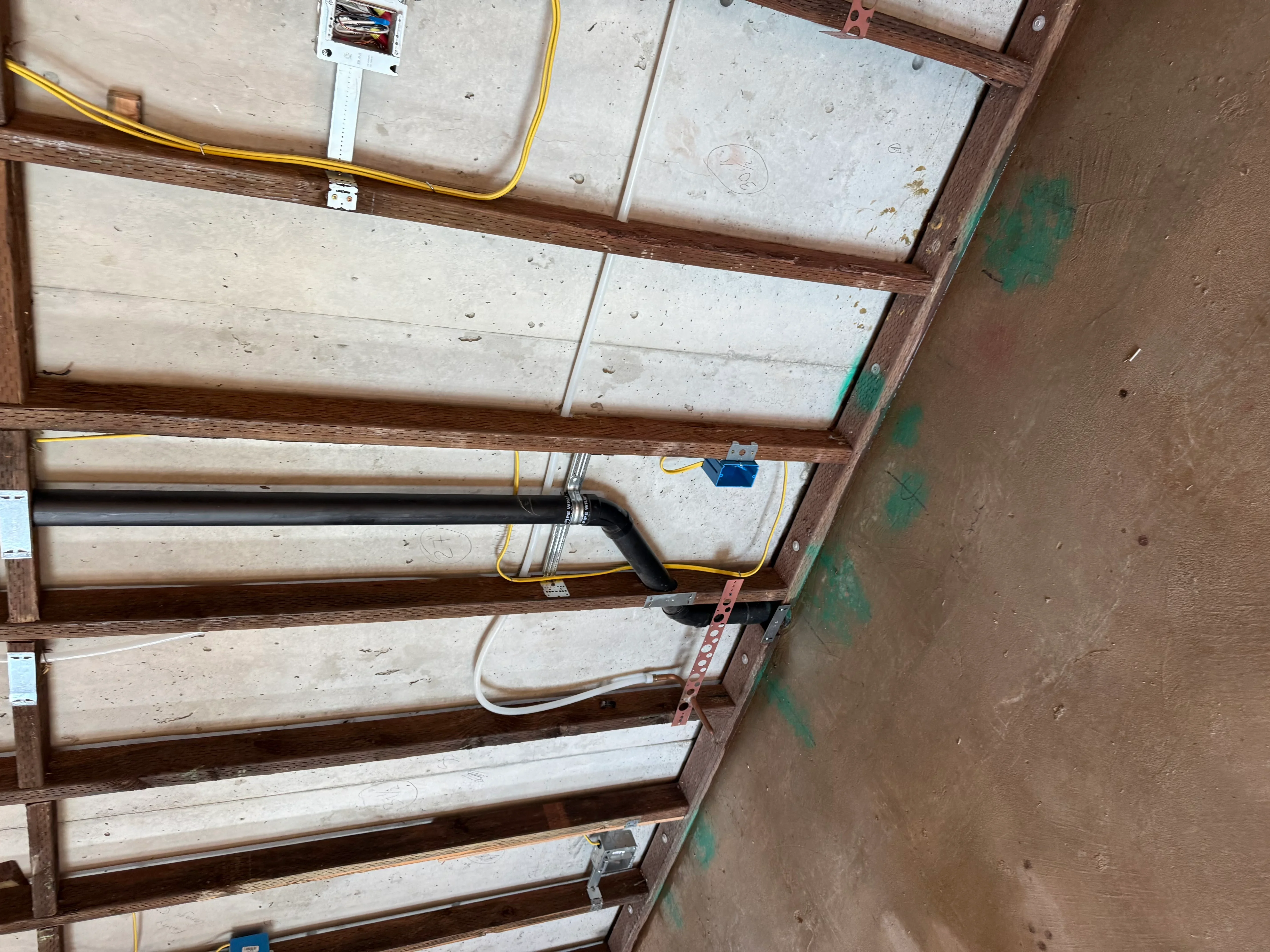 Ceiling electrical rough-in with junction boxes, yellow Romex cable, and organized wiring through wooden joists