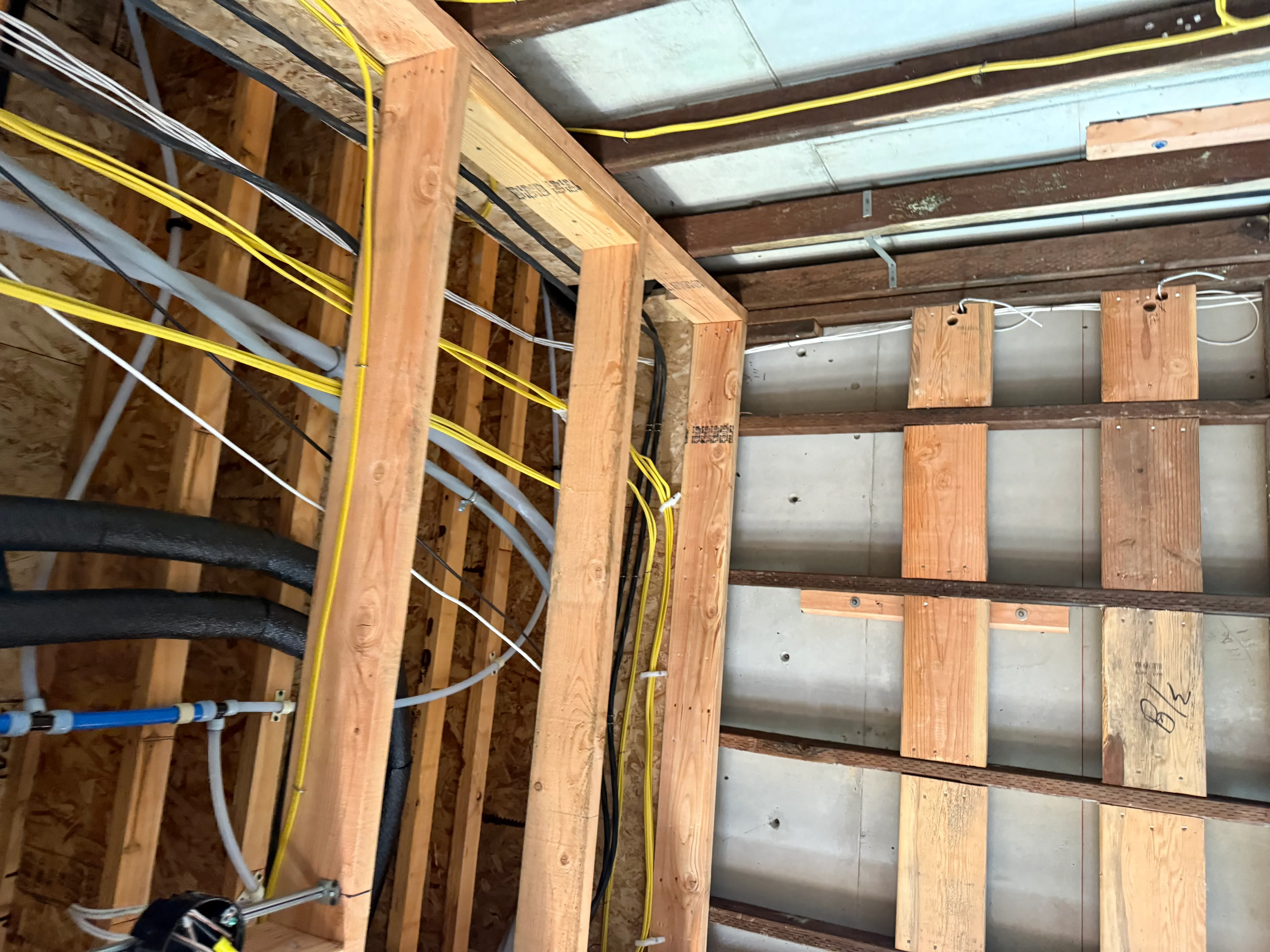 Electrical rough-in with yellow and white Romex cables in wood-framed construction
