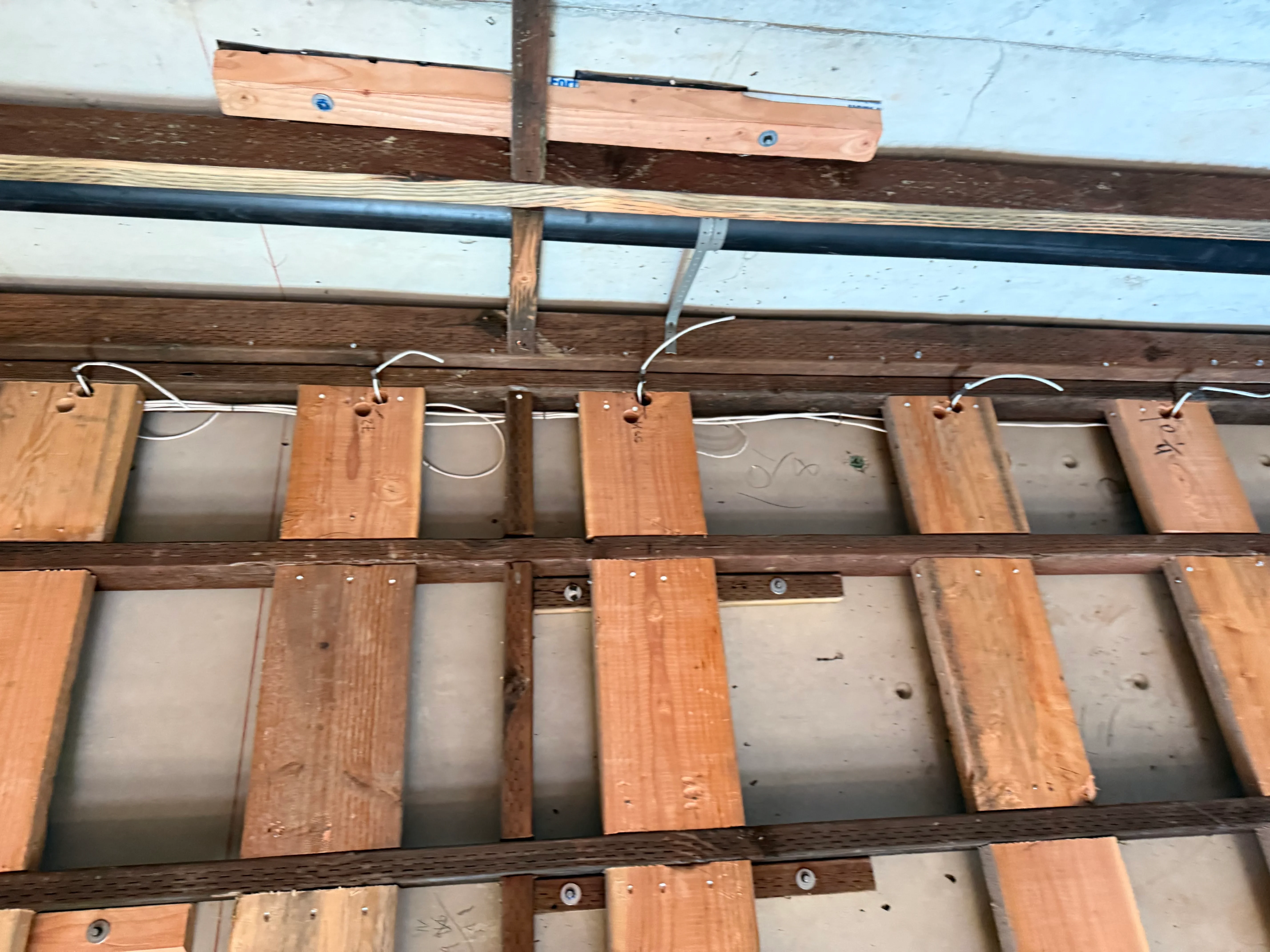 Romex electrical wiring secured to wooden joists with staples and clamps during rough-in phase